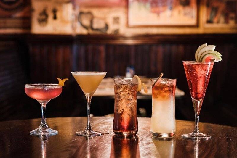 Fünf verschiedene Cocktails auf einem Holztisch im Corinthia St George's Bay Hotel.