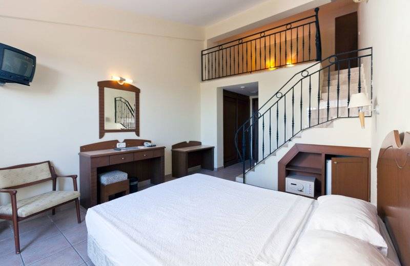 Zimmer im Süral Garden Hotel mit Bett, Schreibtisch, Spiegel und Fernseher.