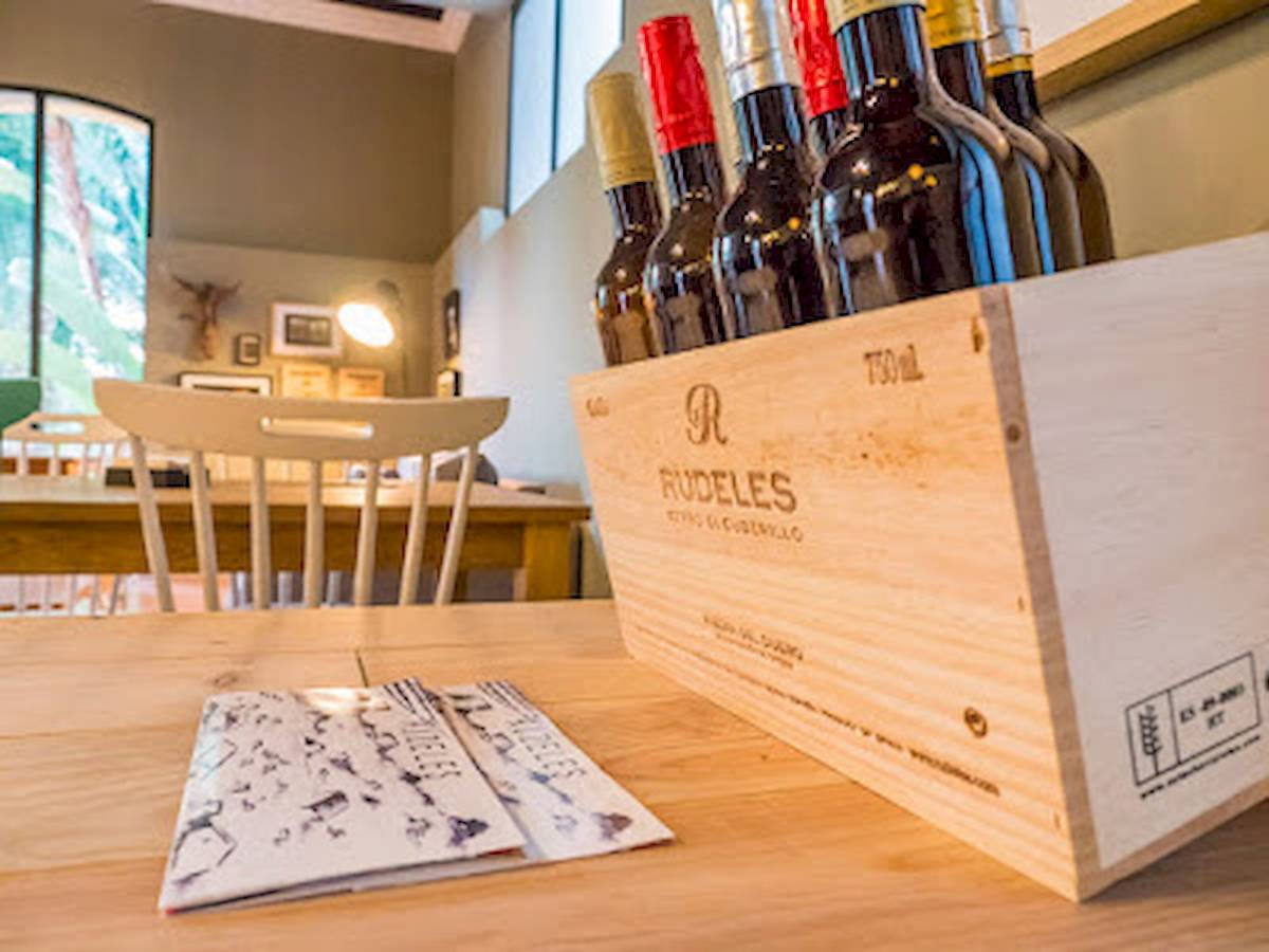 Ein Holzkasten mit Weinflaschen steht auf einem Tisch, daneben sind zwei kleine Karten