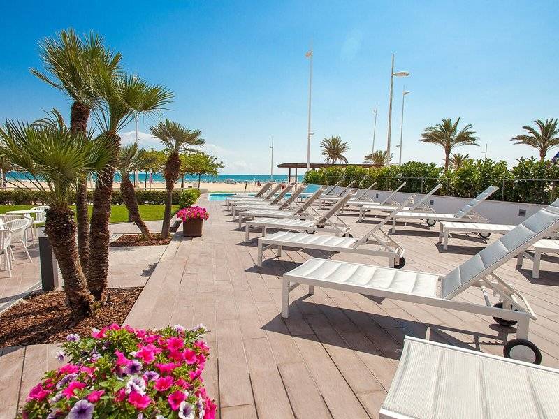 Terrasse des RH Bayren & Spa Hotels mit weißen Liegen und bunten Blumen, Blick auf den Strand