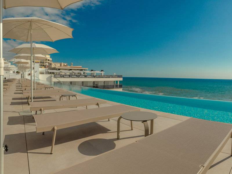Pool-Terrasse des RH Bayren & Spa Hotels mit Sonnenliegen und Sonnenschirmen am Meer