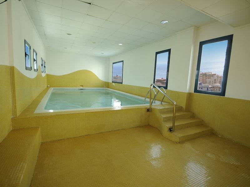 Schwimmbecken im Hotel Principal Afilliated by RH mit gelben Wänden und Fenstern.