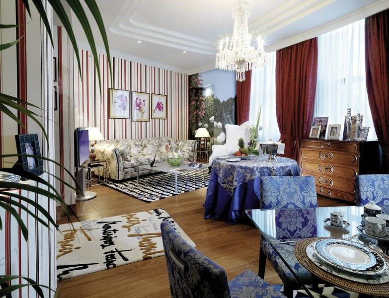 Wohnzimmer im Westin Valencia mit blauen und weißen Mustern, Kristallkronleuchter und rote Vorhänge.