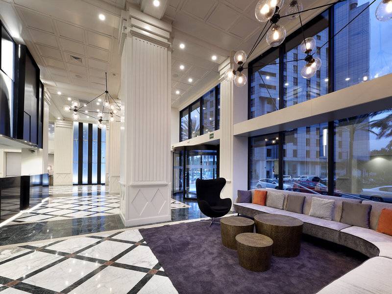 Lobby des Exe Rey Don Jaime Hotels mit modernem Design, weißen Säulen und gemustertem Boden.