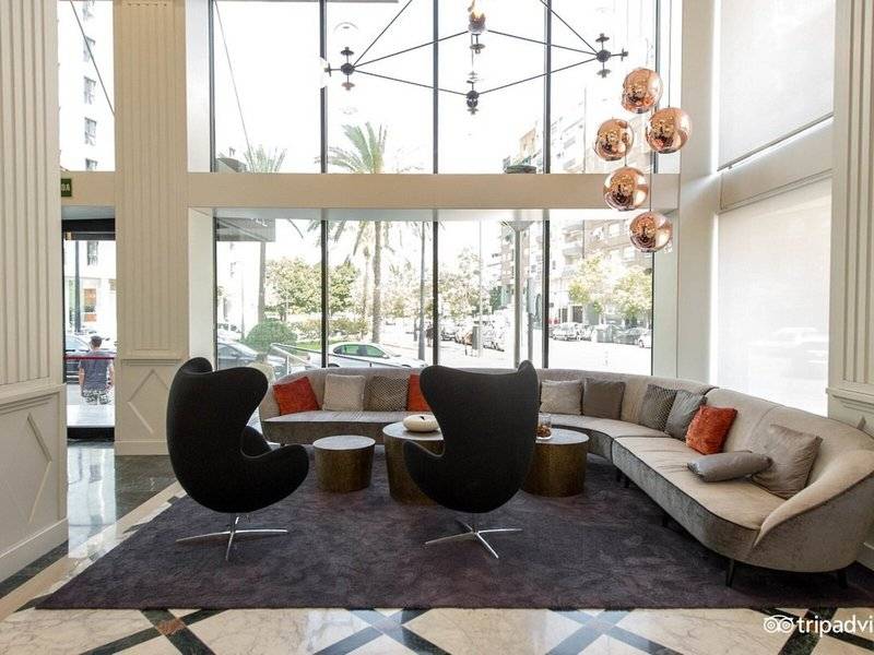 Lobby des Exe Rey Don Jaime Hotels mit moderner Einrichtung und großen Fenstern.