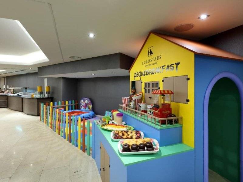 Kinderfrühstück im Exe Rey Don Jaime Hotel mit bunten Gebäuden und Essenstischen