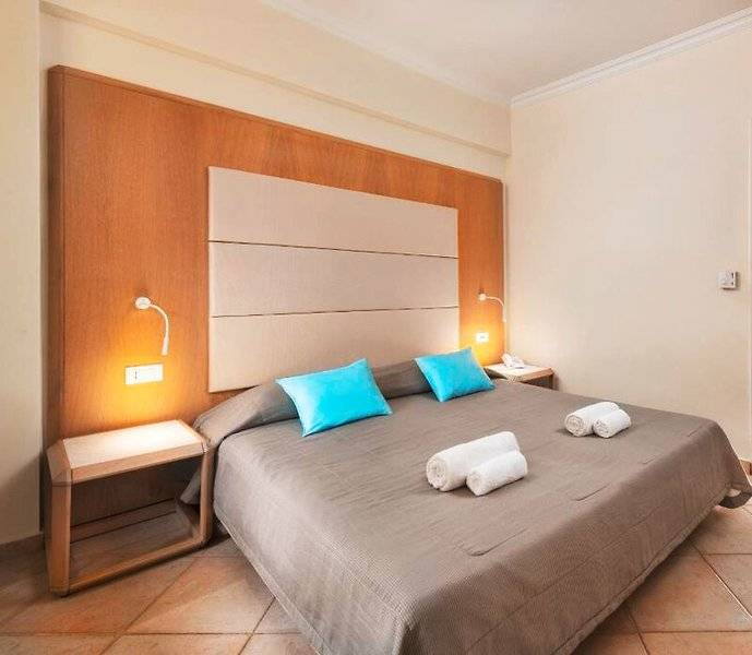 Hotelzimmer im Lindos Royal Resort mit blauen Kissen und grauer Bettwäsche.