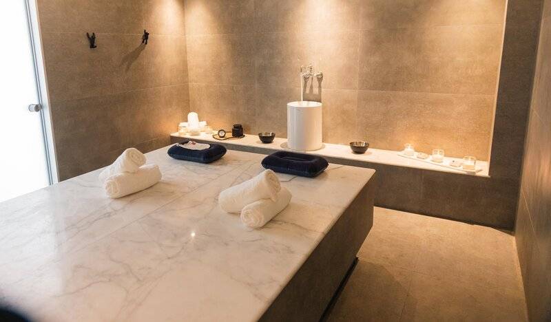 Spa-Behandlungsraum im Lindos Royal Resort mit Marmortisch und blauen Kissen.
