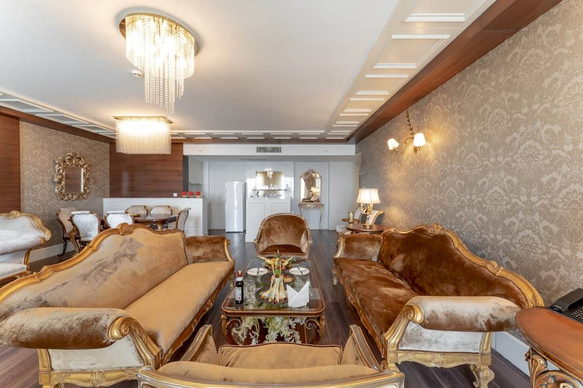 Luxuriöses Wohnzimmer im Sunis Efes Royal Palace Resort & Spa mit goldenen Möbeln, Kristallleuchtern und gemusterten Wänden.