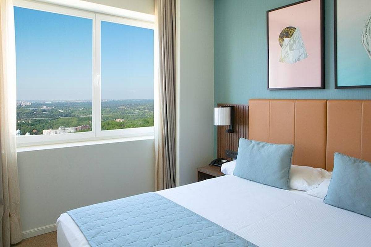 Ausblick aus dem Zimmer des Riu Plaza Espana Hotels mit Fenster, Bett und Stadtsicht.
