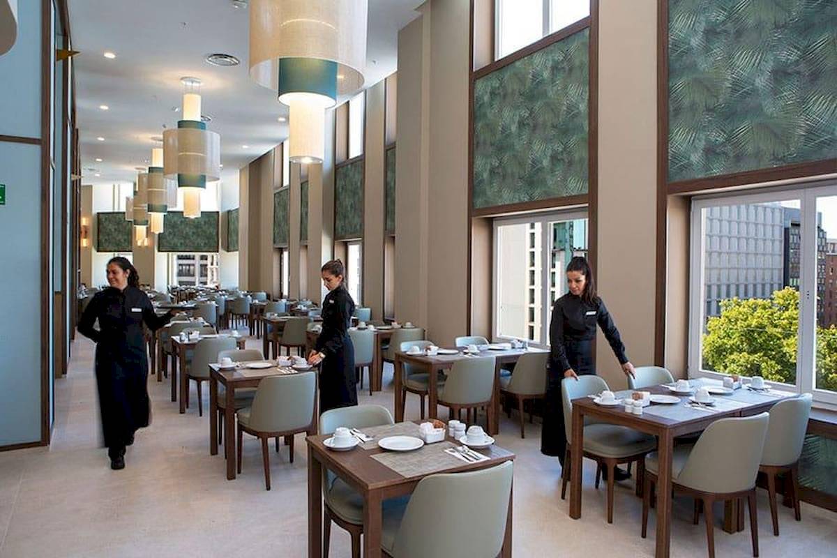 Restaurant im Riu Plaza Espana mit drei Kellnerinnen und gedeckten Tischen