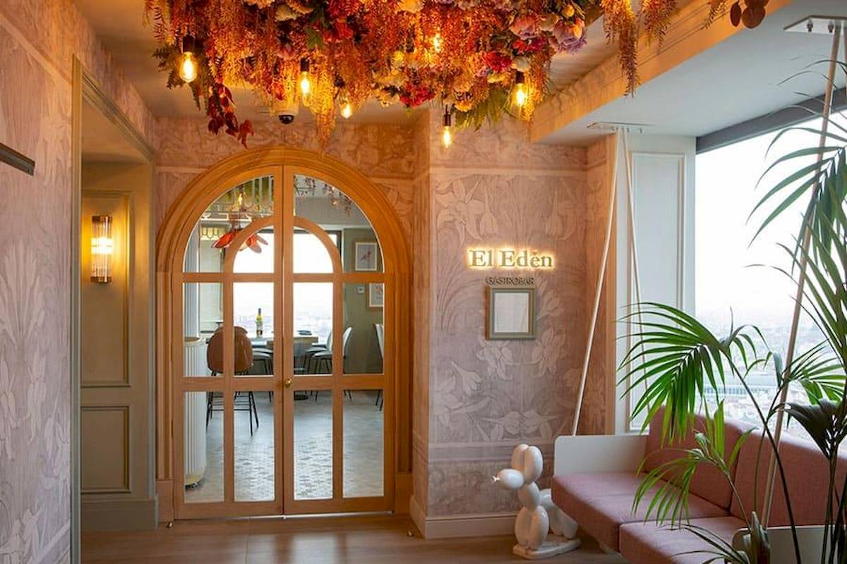 Innenansicht des El Eden im Riu Plaza Espana Hotel mit floraler Decke und rosa Sofas.