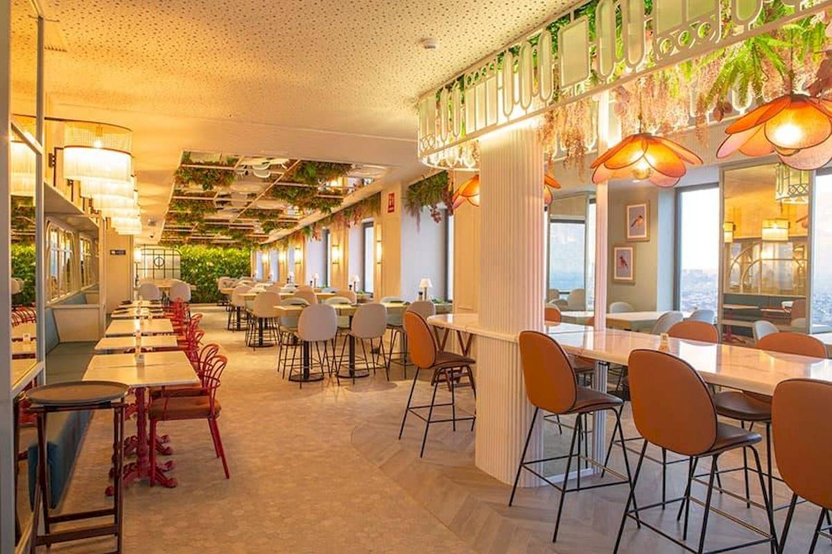 Innenbereich des Riu Plaza Espana Restaurants mit Tischen, Stühlen und grünen Pflanzen an der Decke.