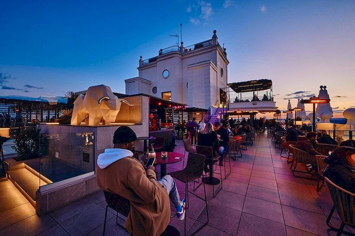 Dachterrasse des Riu Plaza Espana bei Abend, Gäste sitzen an Tischen und genießen die Aussicht.