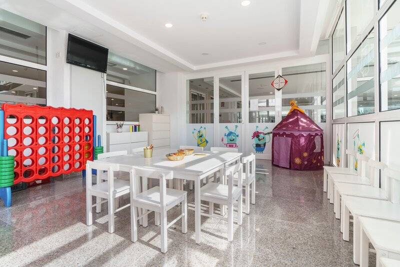 Kinderspielzimmer im ALUA Gran Camp de Mar Hotel mit Tisch, Stühlen und Spielgeräten.
