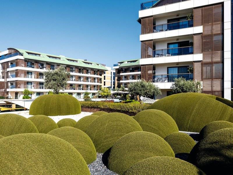 Außenansicht des TUI BLUE Side Hotels mit geformten Hecken und modernen Gebäuden.