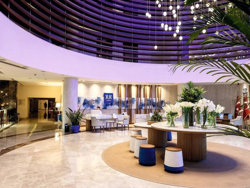 Lobby des TUI BLUE Side Hotels mit moderner Inneneinrichtung, Empfangstresen und Tisch mit Blumen.
