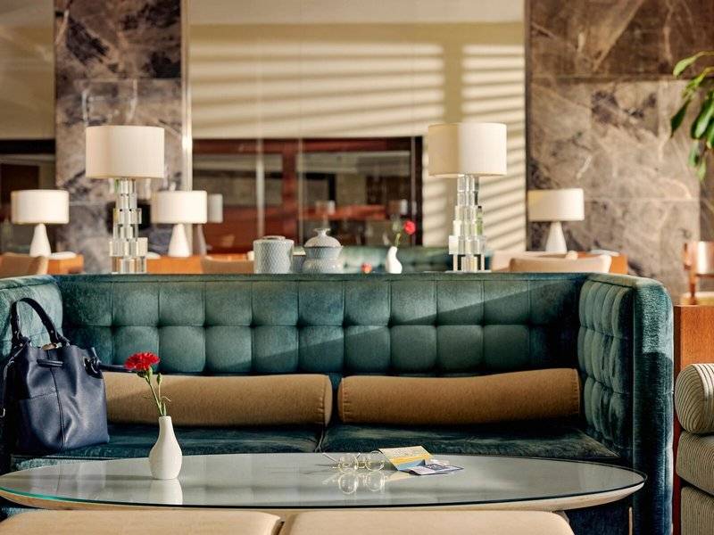 Lobby des TUI BLUE Side Hotels mit grünem Sofa, Tisch und Blumenvase.