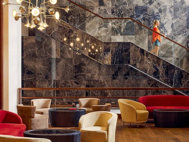 Lobby-Bereich des TUI BLUE Side Hotels mit Marmorwänden, einer Treppe und verschiedenen Sitzmöbeln.
