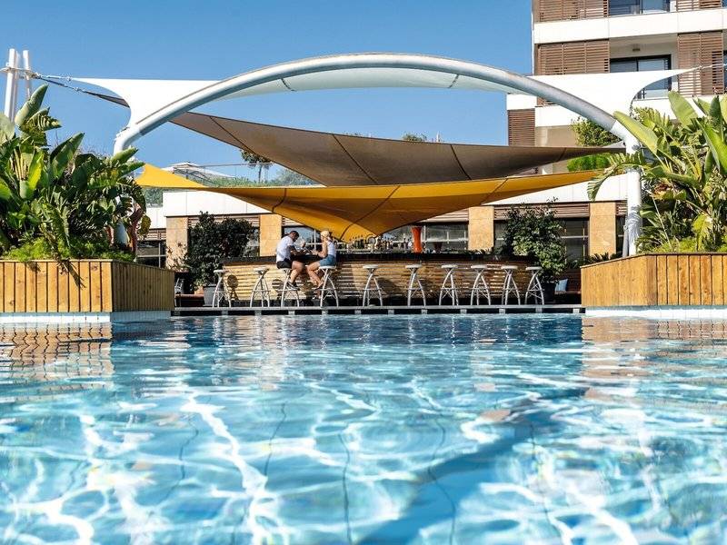 Poolbar im TUI BLUE Side Hotel mit zwei Personen, die unter einem gelben Sonnensegel sitzen