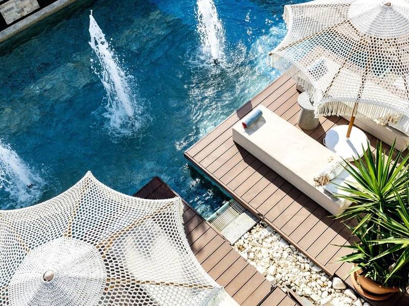 Pool-Terrasse im TUI BLUE Side Hotel mit weißen Sonnenschirmen und einer grünen Pflanze.