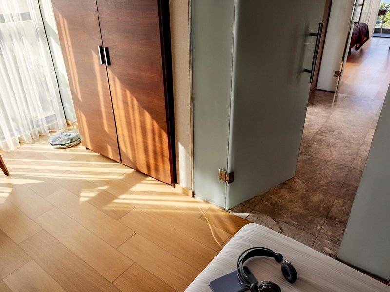 Innenbereich des TUI BLUE Side Hotels mit geräumigem Zimmer, Holzboden, offenem Schrank und Fenstern.