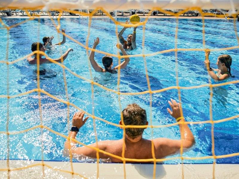 Wasserballspiel im Swimmingpool des Magic Life Jacaranda Hotels mit Spielern und einem Trainer.