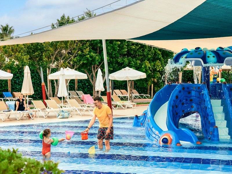 Mann und Kind spielen im Wasser am Pool im Magic Life Jacaranda Hotel