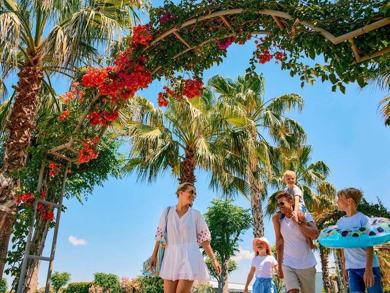 Familie spaziert unter Palmen im Magic Life Jacaranda Hotel