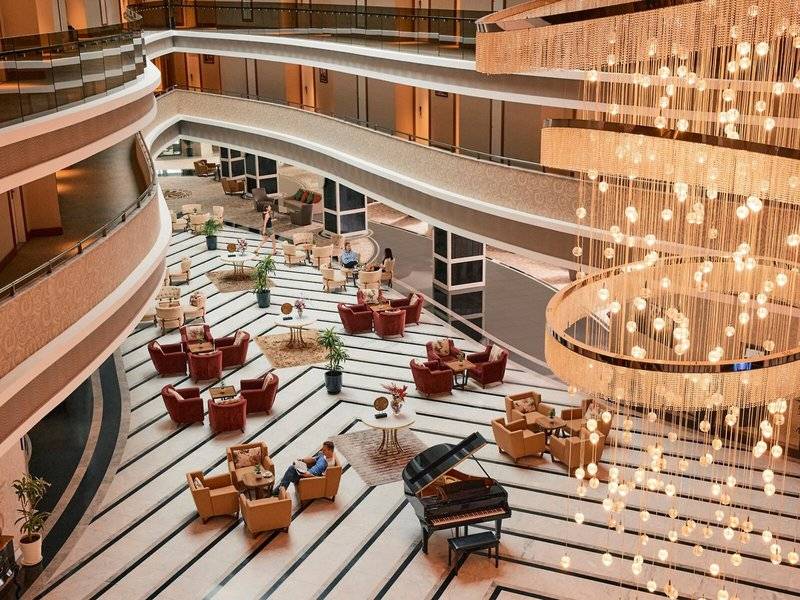 Hotellobby des Magic Life Jacaranda mit Klavier, Kristallleuchte und Loungemöbeln.