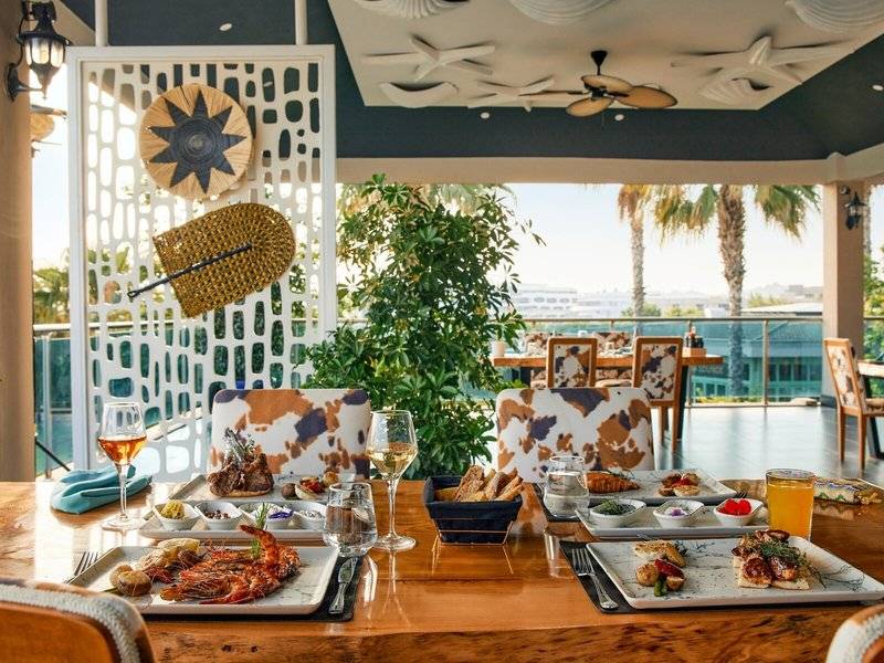 Essen auf einem Tisch im Magic Life Jacaranda Hotel mit verschiedenen Gerichten, Gläsern und Besteck.