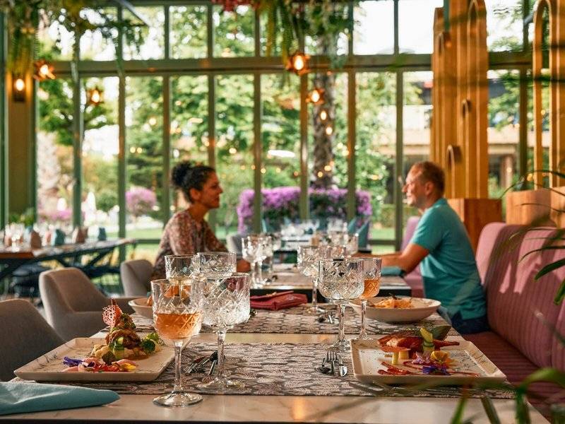 Innenansicht des Restaurants im Magic Life Jacaranda Hotel mit Gästen an einem Tisch.