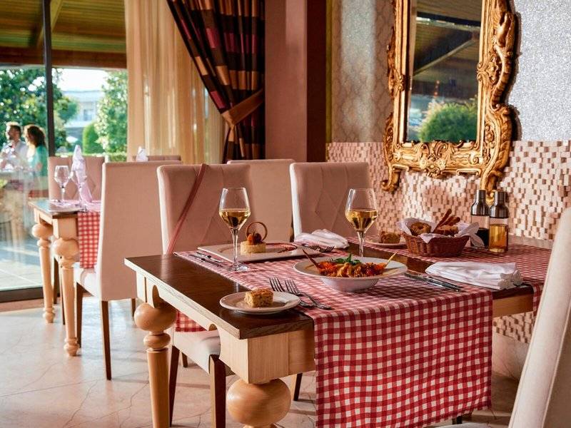 Gedeckter Esstisch im Speisesaal des Magic Life Jacaranda Hotels mit roten Tischdecken und goldenem Spiegel.
