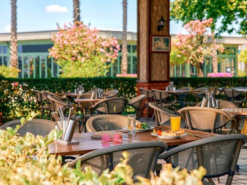 Außenbereich des Magic Life Jacaranda Hotels mit Tischen und Stühlen unter Bäumen