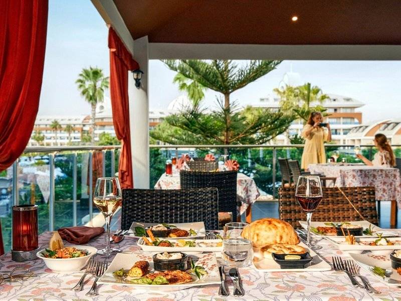 Essen auf der Terrasse im Magic Life Jacaranda Hotel mit Blick auf Palmen und Gebäude.