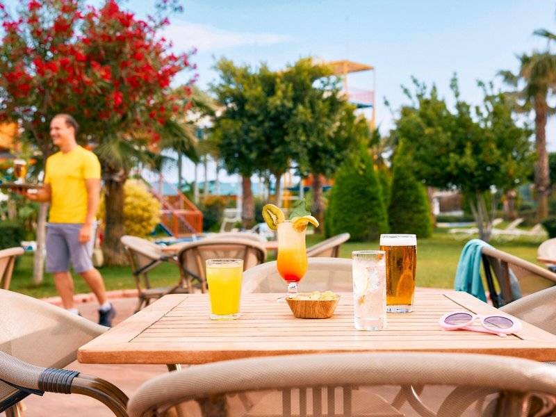 Terrasse im Magic Life Jacaranda Hotel mit Getränken und einem Mitarbeiter.