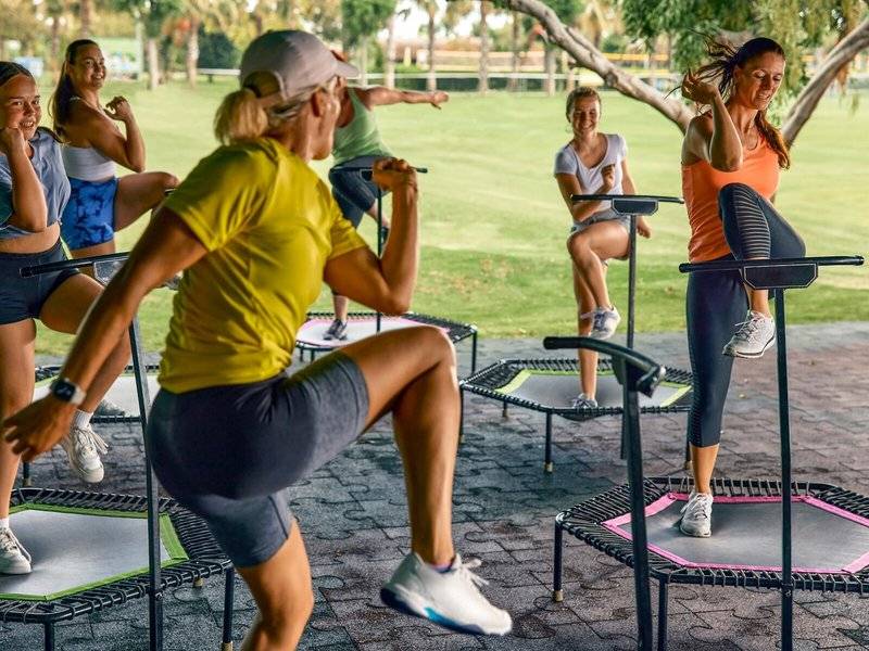 Gruppe von Frauen und Männern, die Fitnesstraining im Freien auf Minitrampolin durchführen.