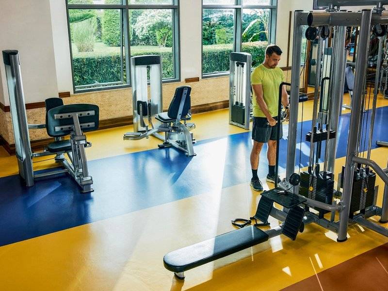 Ein Mann im gelben T-Shirt steht im Fitnessbereich des Magic Life Jacaranda Hotels.