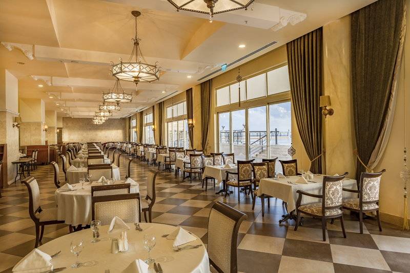 Restaurant im Starlight Resort Hotel mit gemustertem Boden, runden Tischen und Stühlen.