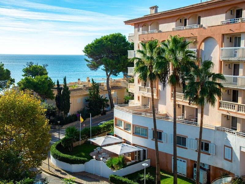 Canyamel Classic Hotel mit Blick auf das Meer und Palmenbäumen.