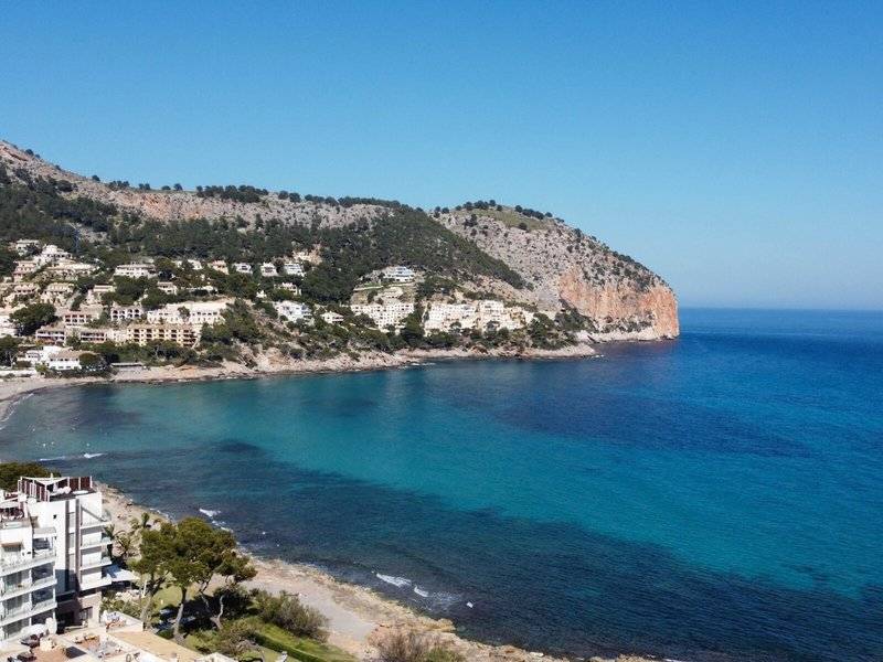 Aussicht auf das Canyamel Classic Hotel und die Bucht mit blauem Meer und grünem Hügel.