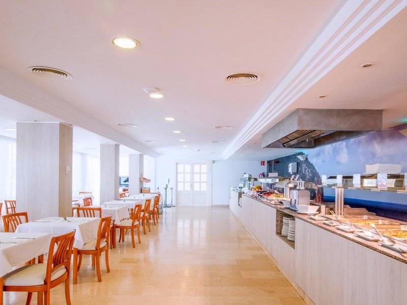 Frühstücksbereich des Canyamel Classic Hotels mit Tisch, Stühlen und Buffet.