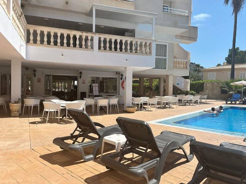 Außenbereich des Canyamel Classic Hotels mit Pool, Liegestühlen und Tischen.