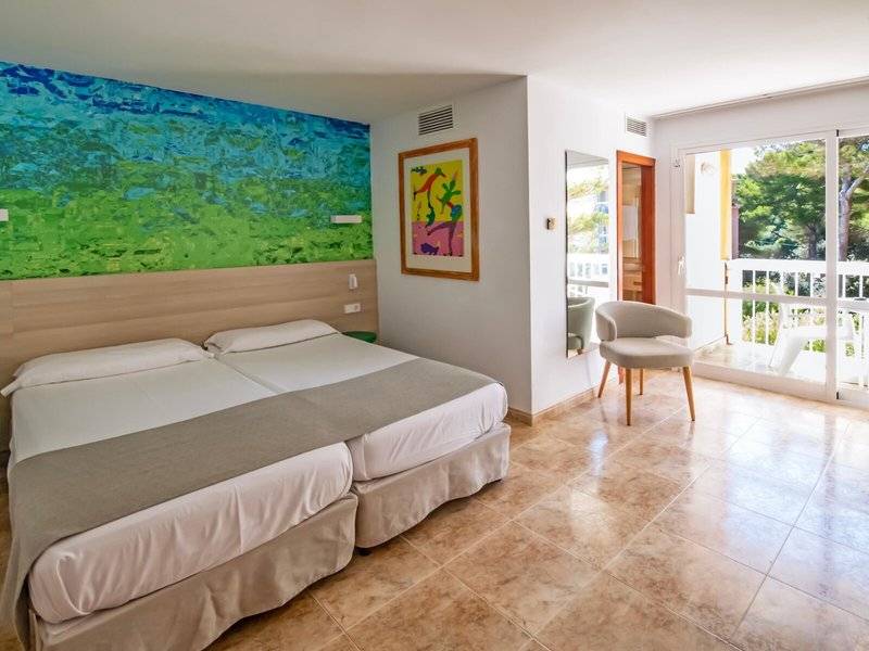 Doppelzimmer im Canyamel Classic Hotel mit zwei Betten, buntem Wandbild, und Zugang zu einer Terrasse.