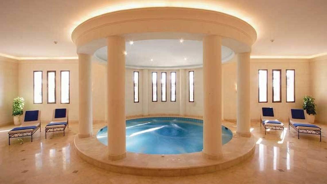 Innenpool im Jaz Belvedere Resort mit runden Säulen und Lounge-Liegen.