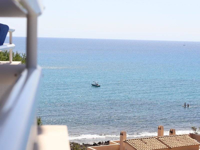 Aussicht vom Balkon auf das Meer mit einem Boot und einem Paar, das badet.