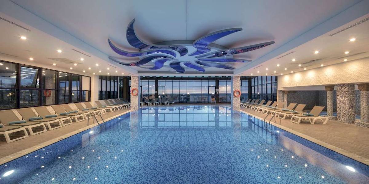 Innenpool des Hotel Granada Luxury Okurcalar mit vielen Liegen und einer modernen Deckengestaltung.