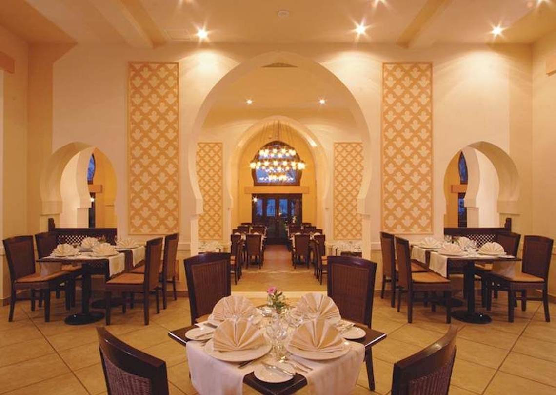 Innenansicht des Restaurants im Jaz Belvedere Resort mit gedeckten Tischen und Stühlen.