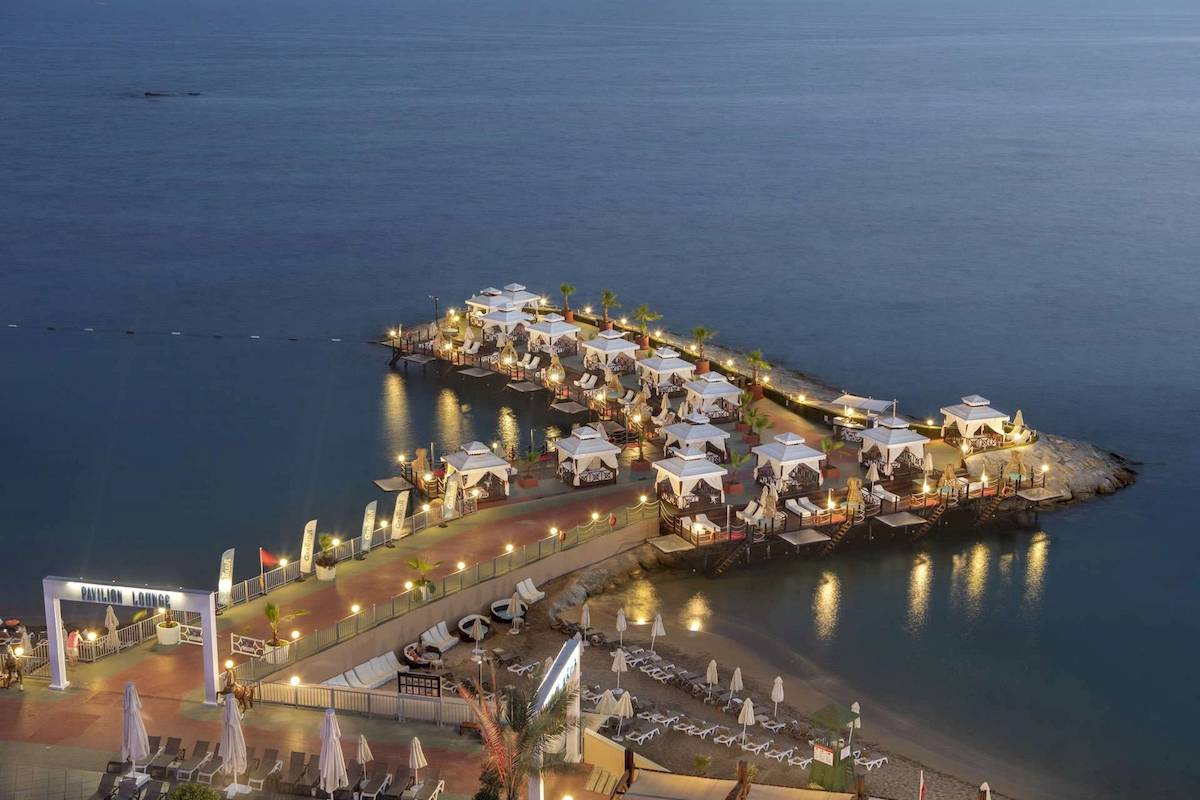 Abendliche Außenansicht des Granada Luxury Okurcalar Hotels mit Pavillons am Meer