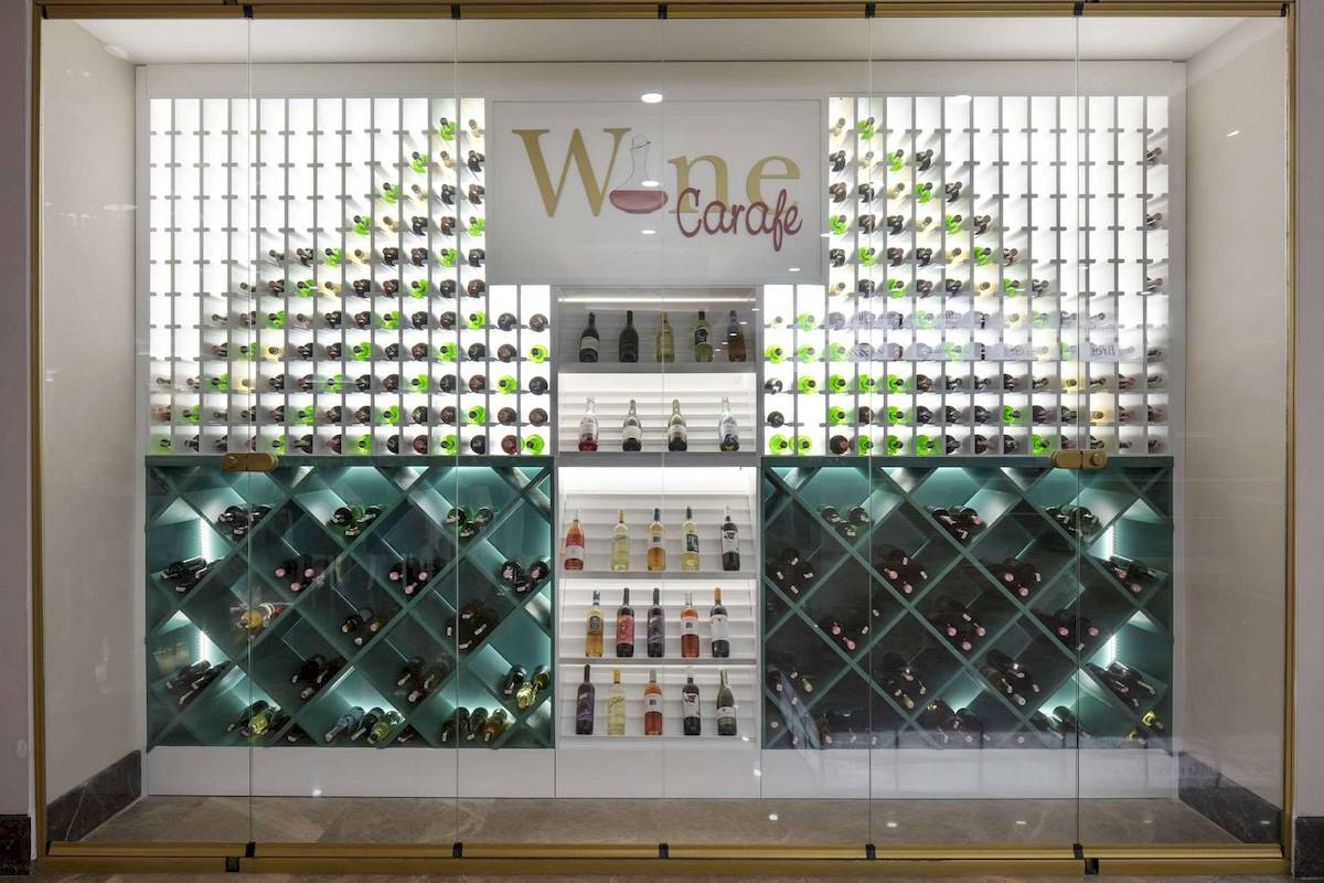 Weinkeller im Granada Luxury Okurcalar Hotel mit grün beleuchteten Flaschen und 'Wine Carafe' Schild.